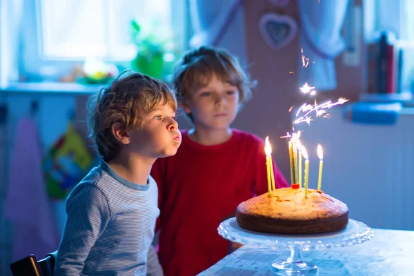 小家伙男孩双胞胎庆祝生日，蛋糕上吹蜡烛 — 图库照片