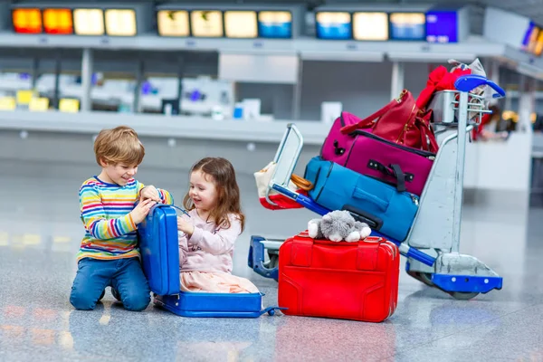 Two little kids, boy and girl going on vacations trip with suitcase at airport — Stock Photo, Image