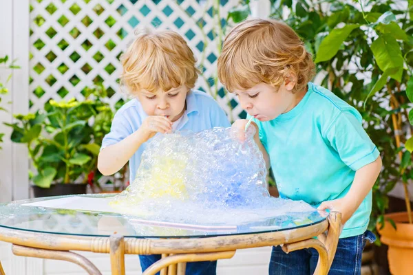Duas crianças felizes fazendo experiências com bolhas coloridas — Fotografia de Stock