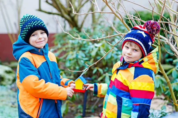 Två kids lite pojkar hängande fågel hus på träd för utfodring i w — Stockfoto