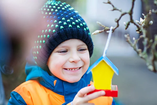 Kleines Kind hängt Vogelhaus an Baum zum Füttern im Winter — Stockfoto
