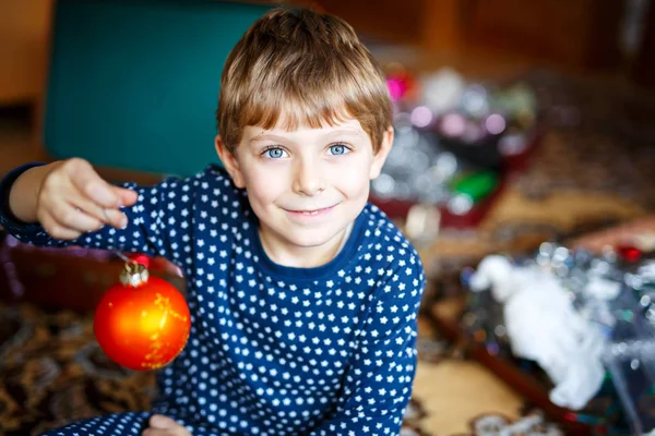Милий маленький хлопчик прикрашає ялинку різнокольоровими кульками — стокове фото