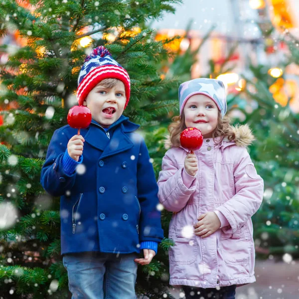 Dvě malý děti jíst cukr apple na vánoční trh — Stock fotografie