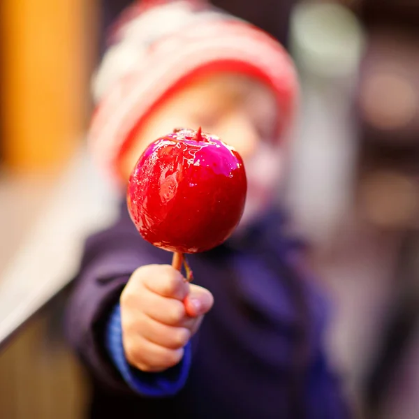 Menino pequeno comendo maçã doce no mercado de Natal — Fotografia de Stock