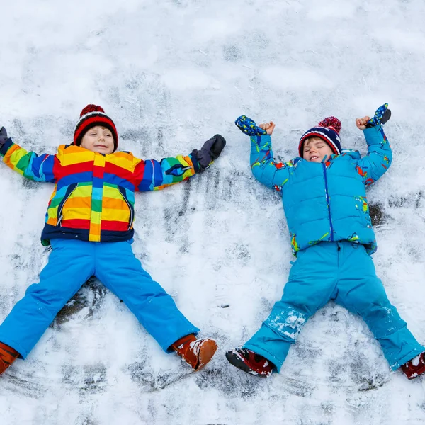 Two little kid boys making snow angel in winter, outdoors — Stock Photo, Image