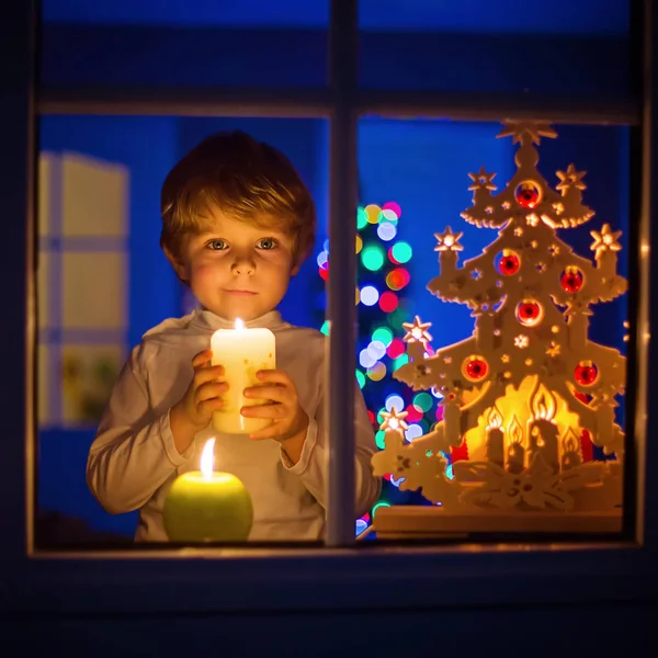 Ragazzino in piedi vicino alla finestra a Natale e tenendo — Foto Stock