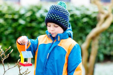 Küçük çocuk çocuk kuş evi kış aylarında beslenme için ağaç üzerinde asılı