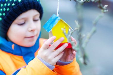 Küçük çocuk kuş evi kış aylarında beslenme için ağaç üzerinde asılı