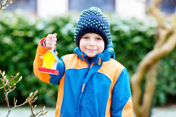 Niño colgando casa de pájaros en el árbol para alimentarse en invierno —  Fotos de Stock