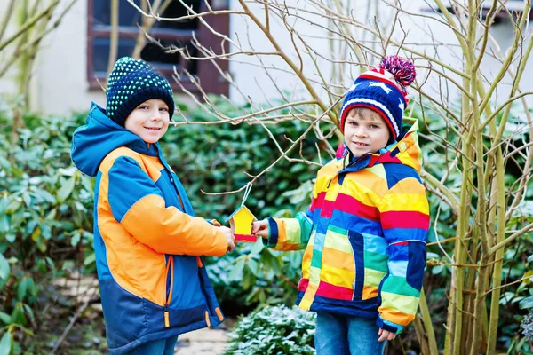 Two little kids boys hanging bird house on tree for feeding in winter — Stock Photo, Image