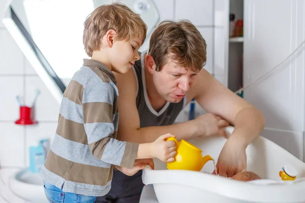 Kleiner Junge und junger Vater baden Neugeborenes — Stockfoto