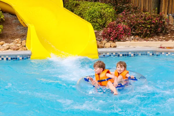 Niños emocionados en el parque acuático montar en tobogán con flotador — Foto de Stock
