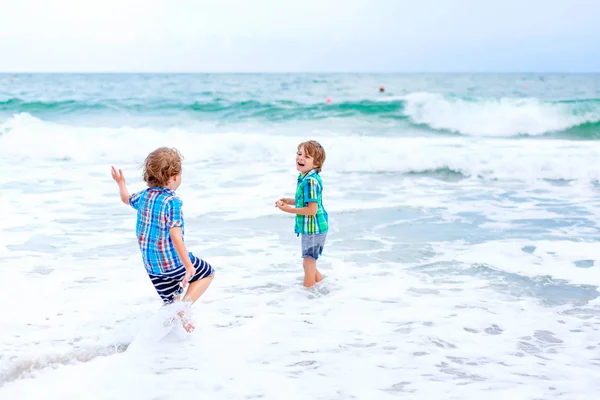 Dos niños pequeños corriendo en la playa del océano — Foto de Stock