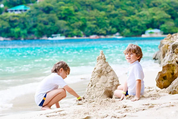 Tropik sahilde kum kale iki çocuk çocuklar — Stok fotoğraf