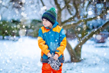 Mutlu çocuk kışın karla eğleniyor.
