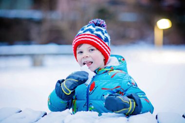 Mutlu çocuk kışın karla eğleniyor.