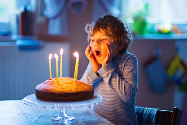 Маленький мальчик празднует свой день рождения и задувает свечи на торте — стоковое фото