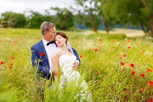 Happy wedding couple in pink poppy field — Stock Photo, Image