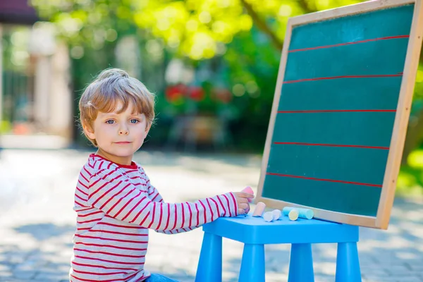 Little boy at blackboard practicing letters — Stock Photo, Image