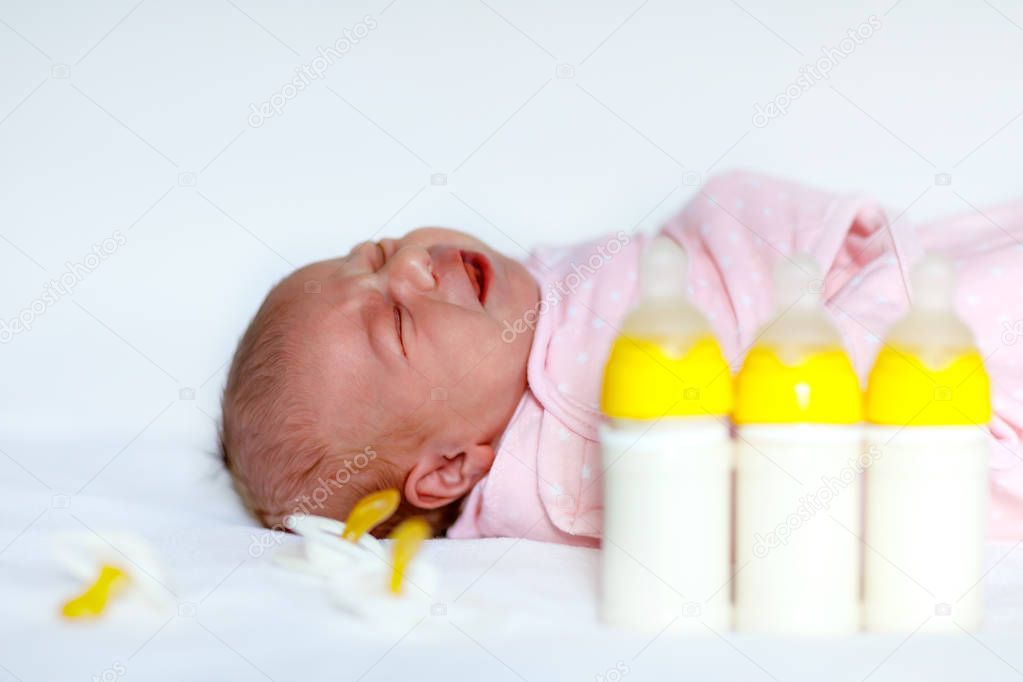 Cute newborn baby girl with nursing bottles and pacifier