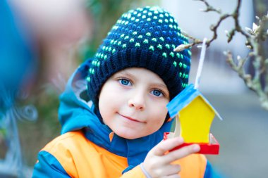 Küçük çocuk kuş evi kış aylarında beslenme için ağaç üzerinde asılı