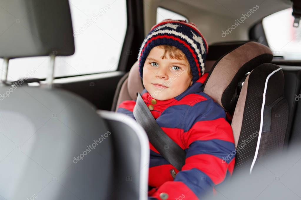 Little kid boy sitting in safety car seat during trip