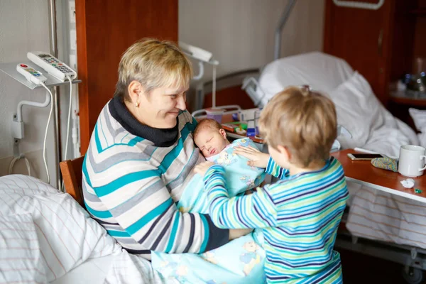 Abuela y niño niño sosteniendo nieto bebé recién nacido en brazos — Foto de Stock