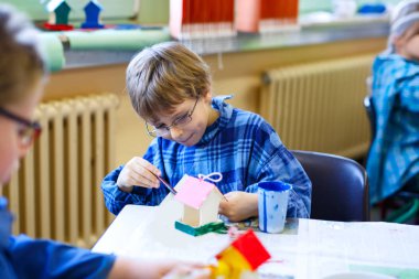 Küçük okul çocuk çocuk gözlüklü kuş evi suluboya ile boyama