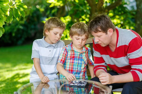Dva malý kluk chlapci a otec hrát dáma hra — Stock fotografie