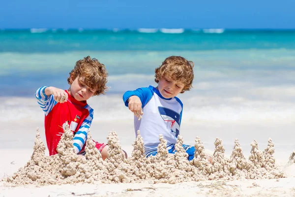 Twee jongen jongens bouwen van zandkasteel op tropisch strand — Stockfoto