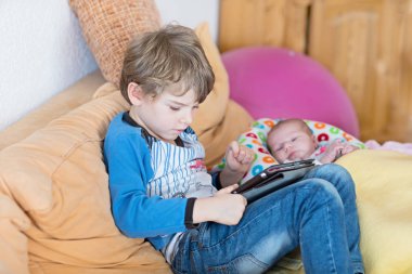 Okul öncesi çocuk çocuk oyun oynarken tablet bilgisayara. Şirin yeni doğan bebek kardeşim arıyor.