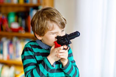Sevimli küçük okul öncesi çocuk çocuk evde silahla oynarken,