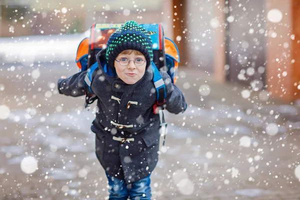 Menino feliz se divertindo com neve a caminho da escola — Fotografia de Stock