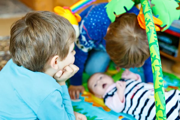 Duas crianças meninos brincando com bebê recém-nascido irmã menina — Fotografia de Stock