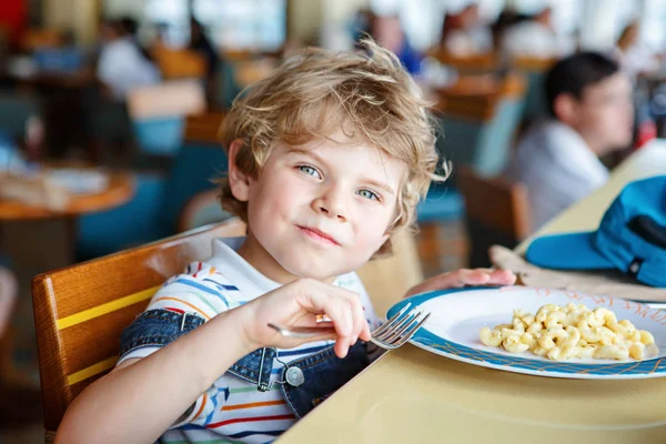 Bonito menino pré-escolar saudável come massa sentada na cantina da escola — Fotografia de Stock