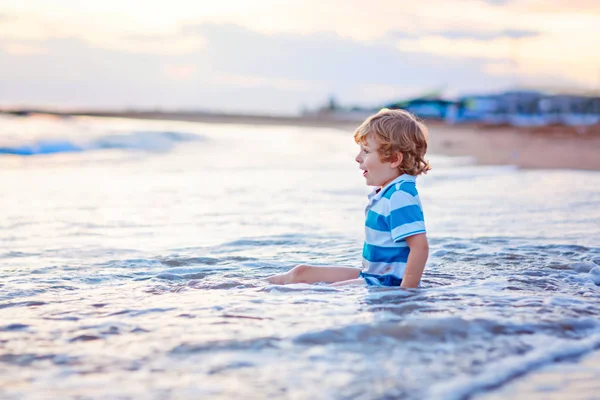 Happy little kid boy having fun with water and wafe on beach ocean — Stock Photo, Image