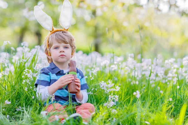 Klein kind met Easter bunny oren en chocolade — Stockfoto
