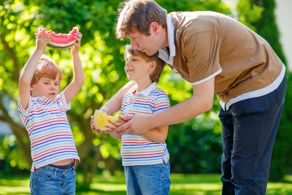 Due piccoli bambini in età prescolare ragazzi e padre mangiare anguria — Foto Stock