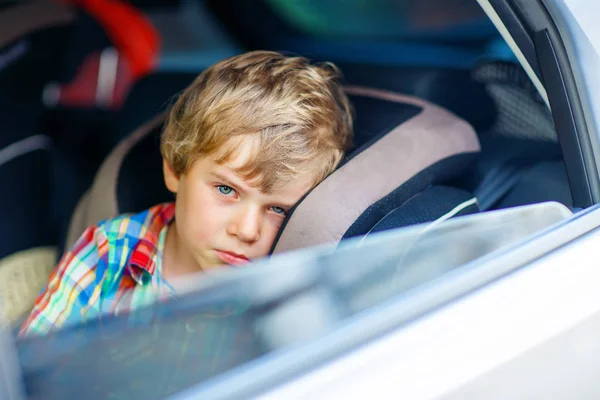 Triste menino cansado sentado no carro durante o engarrafamento — Fotografia de Stock