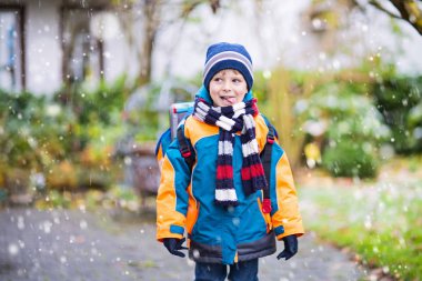 Mutlu çocuk okula giderken karla eğleniyor.