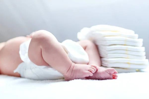 Feet of newborn baby on changing table with diapers — Stock Photo, Image