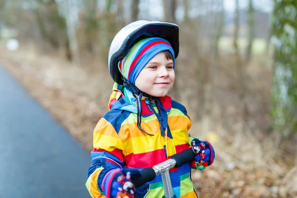 Cute preschool kid boy riding on scooter in park — Stock Photo, Image