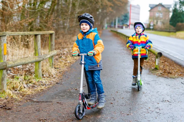 Dos niños pequeños, mejores amigos montando en scooter en la ciudad —  Fotos de Stock