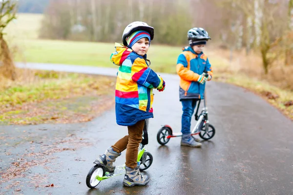 Dos niños pequeños, mejores amigos montando en scooter en el parque —  Fotos de Stock