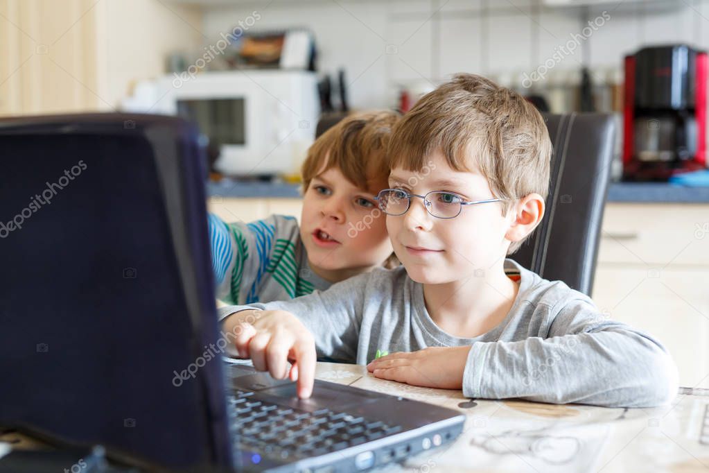 Two kids boys playing online and surfing in internet on computer