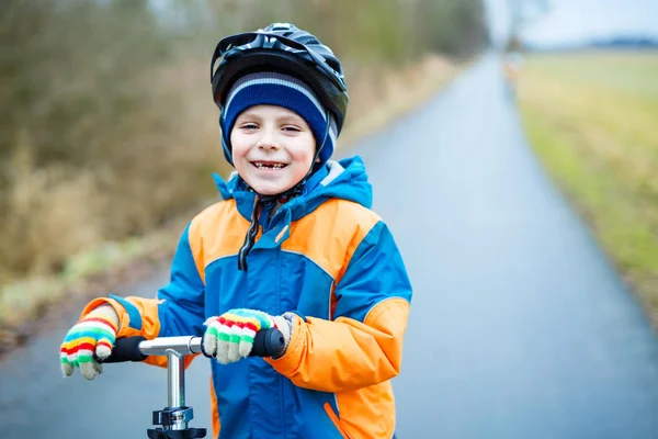 Cute preschool kid boy riding on scooter in park — Stock Photo, Image