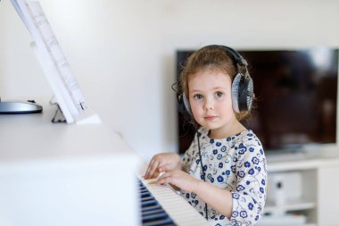 Güzel küçük çocuk kız oturma odası veya müzik okulu piyano