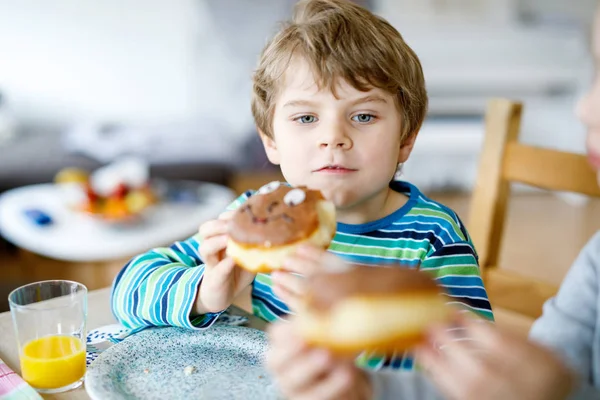 Adorable niño preescolar comiendo donut indoor —  Fotos de Stock