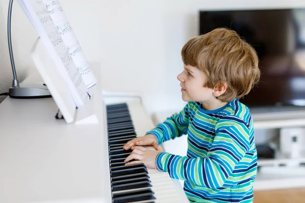 Vacker liten unge pojke spela piano i vardagsrum eller musikskola — Stockfoto