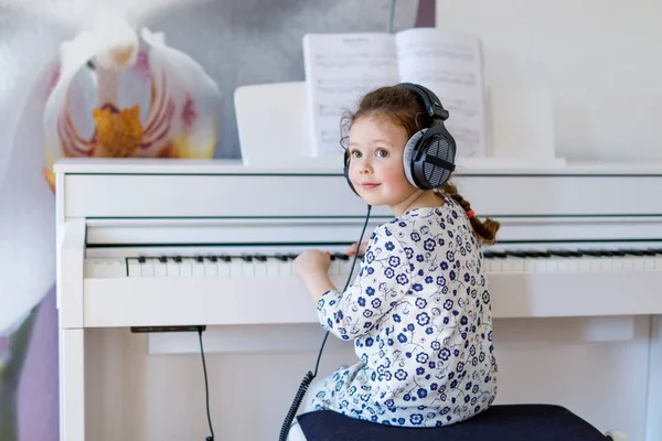 Beautiful little kid girl playing piano in living room or music school — Stock Photo, Image